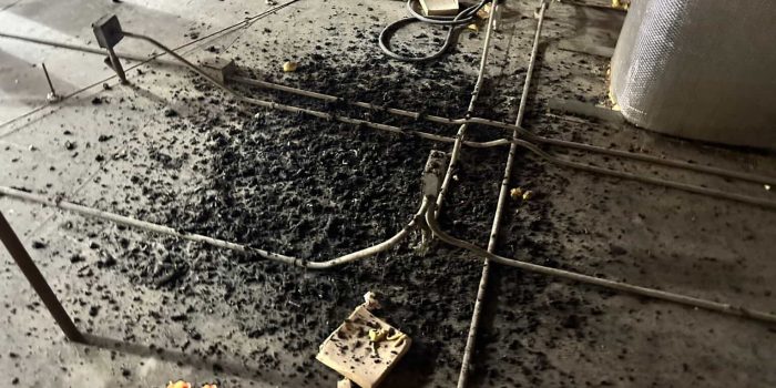 Black insulation debris scattered around exposed electrical conduits and cables on concrete construction floor