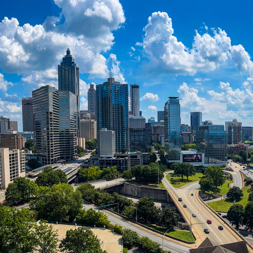 Downtown Atlanta skyline with high-rise buildings, winding highway and blue sky with puffy clouds