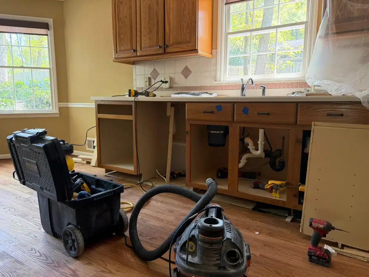 Kitchen cabinets opened with plumbing exposed during restoration