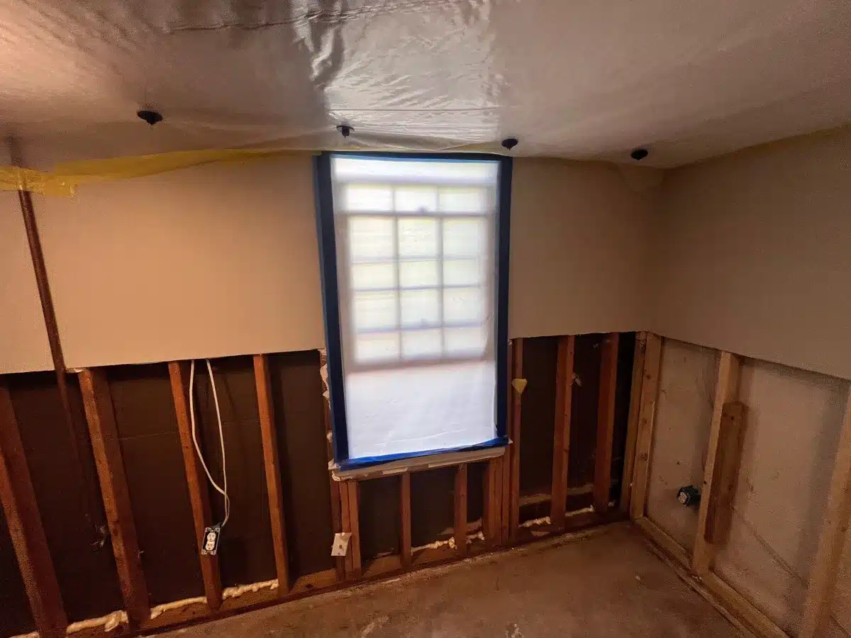 Lower drywall removed exposing wall studs and subfloor